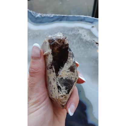 Hand holding rare Brazilian smokey quartz point with lodalite inclusions