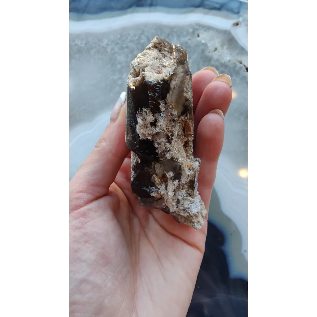 Hand holding rare Brazilian smokey quartz point with lodalite inclusions