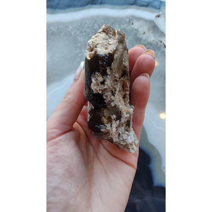 Hand holding rare Brazilian smokey quartz point with lodalite inclusions