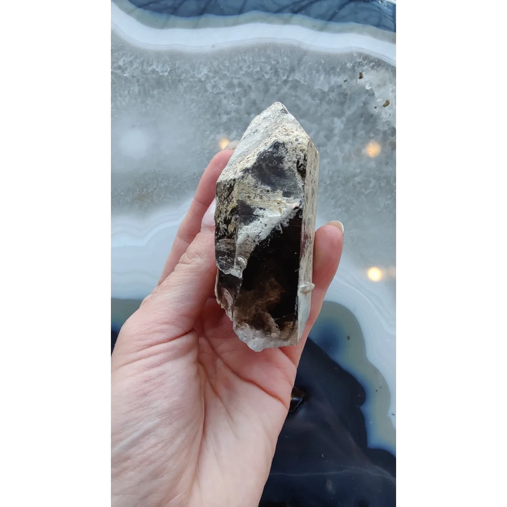Hand holding rare Brazilian smokey quartz point with lodalite inclusions