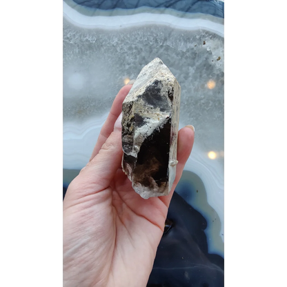 Hand holding rare Brazilian smokey quartz point with lodalite inclusions