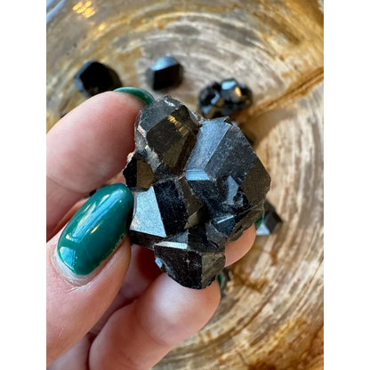 Hand holding rare melanite garnet crystals from Kayes Region, Mali