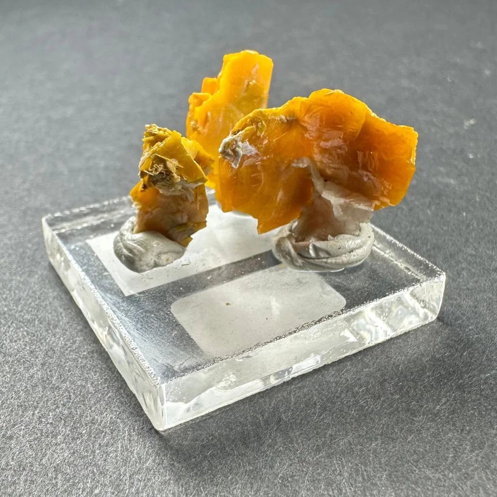 Vibrant orange-yellow citrine-like Moroccan wulfenite crystals on acrylic base