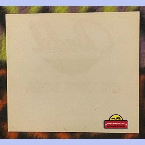 Faded cream paper label back with partial ghost image of orange fruit visible.