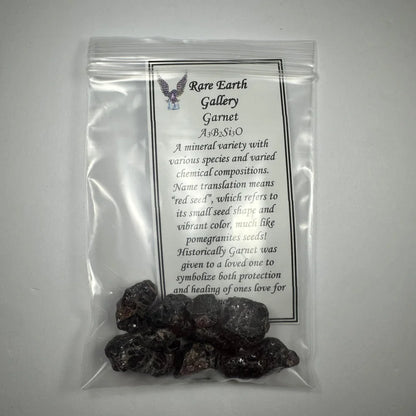 Dark rough-textured garnet stones in clear bag with label, raw deep red and purple collection