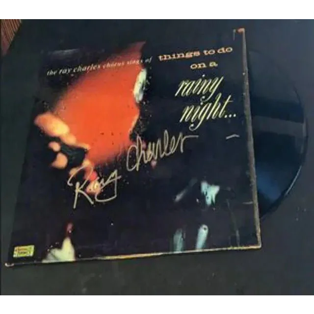 Dark vinyl record in worn album cover with orange design from Ray Charles Autographed Rainy Night vinyl