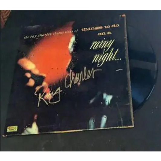 Dark vinyl record in worn album cover with orange design from Ray Charles Autographed Rainy Night vinyl