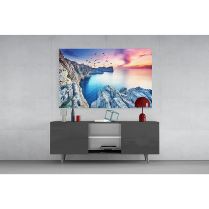 Vibrant glass wall art of coastal cliffs, blue sea, and sunset sky with birds