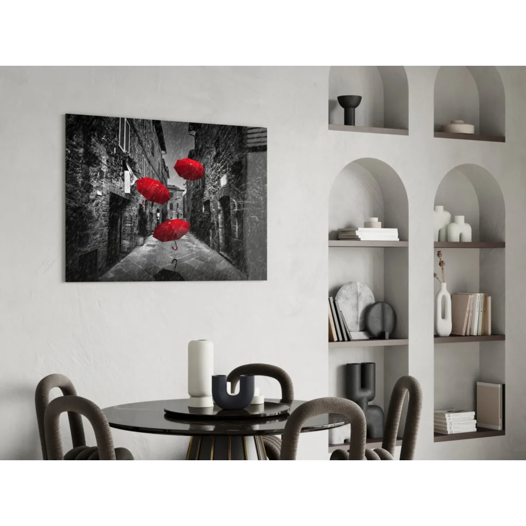 Black and white wall art of red umbrellas floating in cobblestone alley