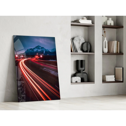 Vibrant glass wall art of nighttime mountain highway with red light trails