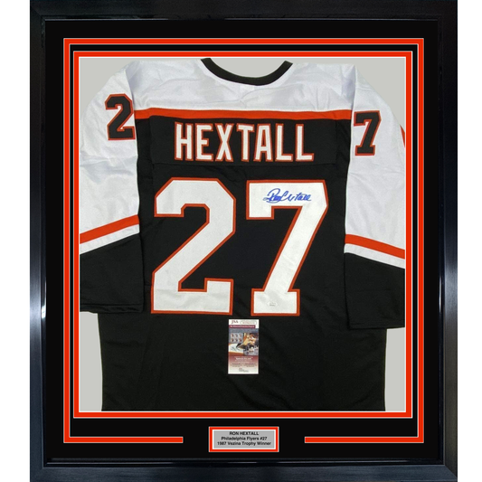 Framed black Philadelphia Flyers hockey jersey #27 signed by Ron Hextall with white and orange trim, displayed flat against white matting.