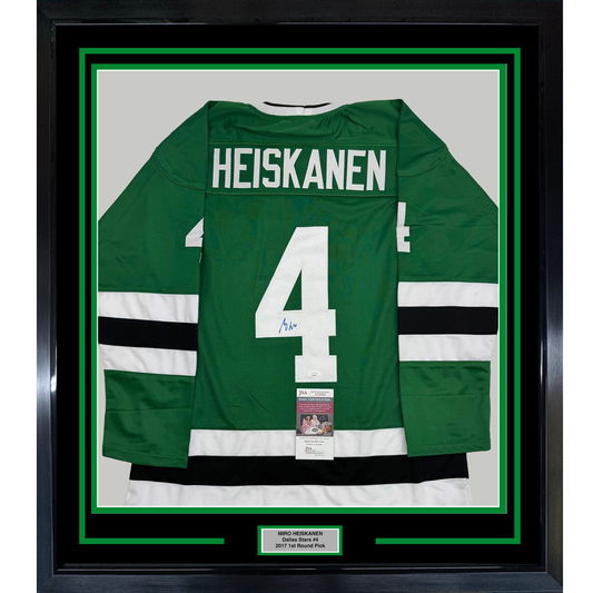 Framed green Dallas Stars hockey jersey number 4 with "HEISKANEN" nameplate, white and black stripes, displayed against white matting with JSA authentication certificate visible.
