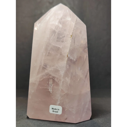A translucent pink rose quartz polished obelisk tower with faceted geometric design and natural internal inclusions