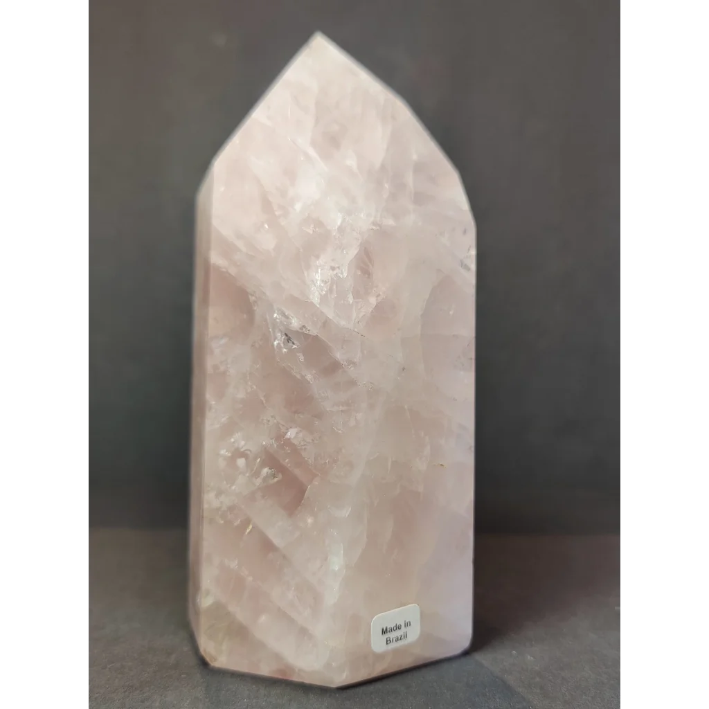 Rose quartz polished obelisk tower sculpture with a translucent pink faceted geometric design and natural inclusions