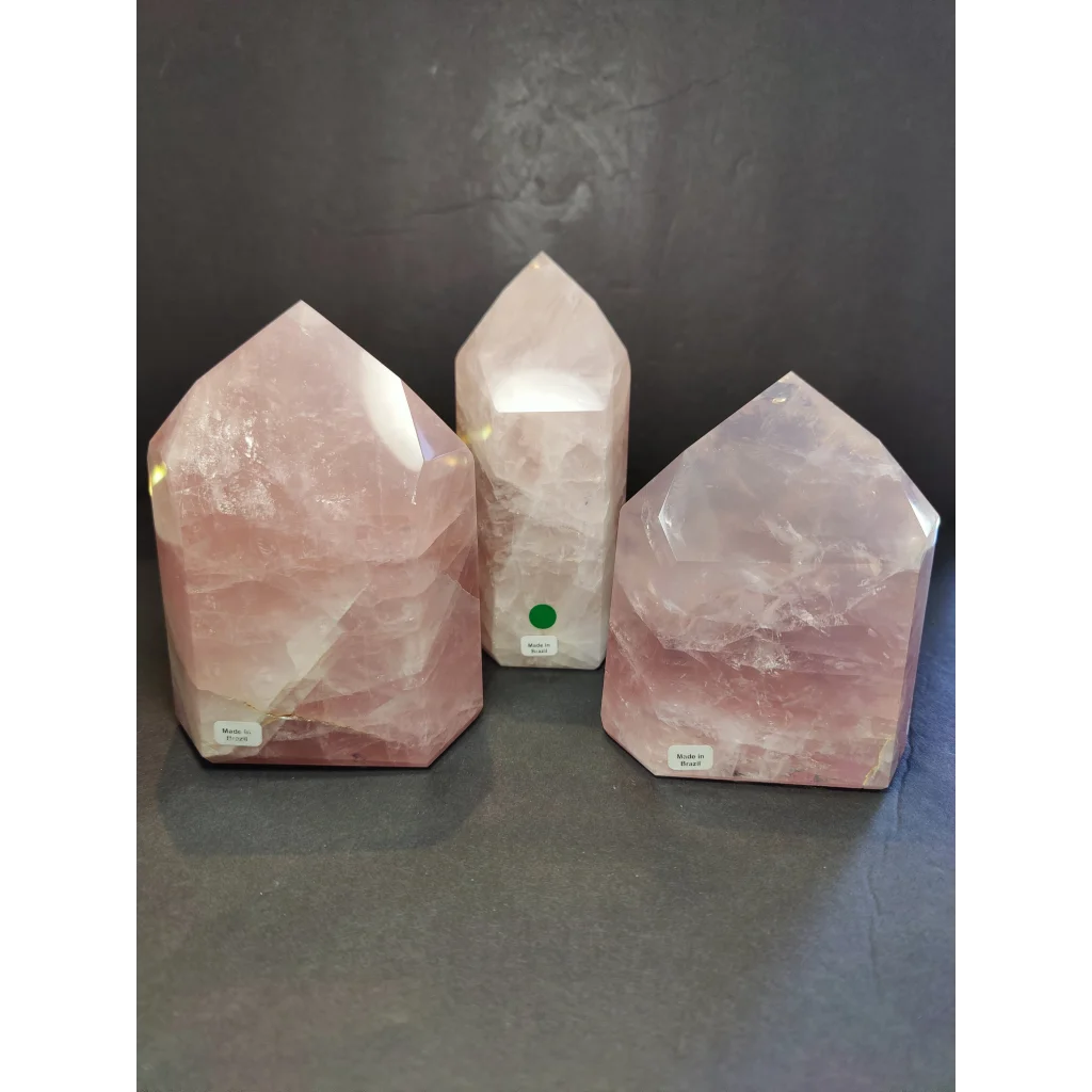 Three rose quartz polished obelisk towers with faceted geometric design and natural pink hues displayed upright