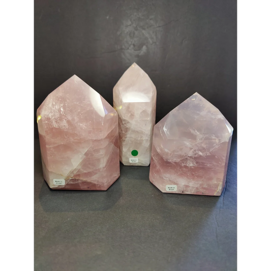 Three rose quartz polished obelisk towers with faceted geometric design and natural pink hues displayed upright