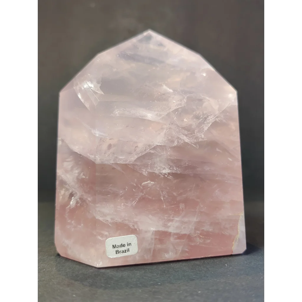 A rose quartz polished obelisk tower with a translucent pink faceted geometric shape and natural internal striations