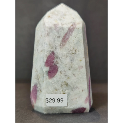 A quartz polished obelisk tower sculpture featuring a translucent white crystal with pinkish red rubellite inclusions