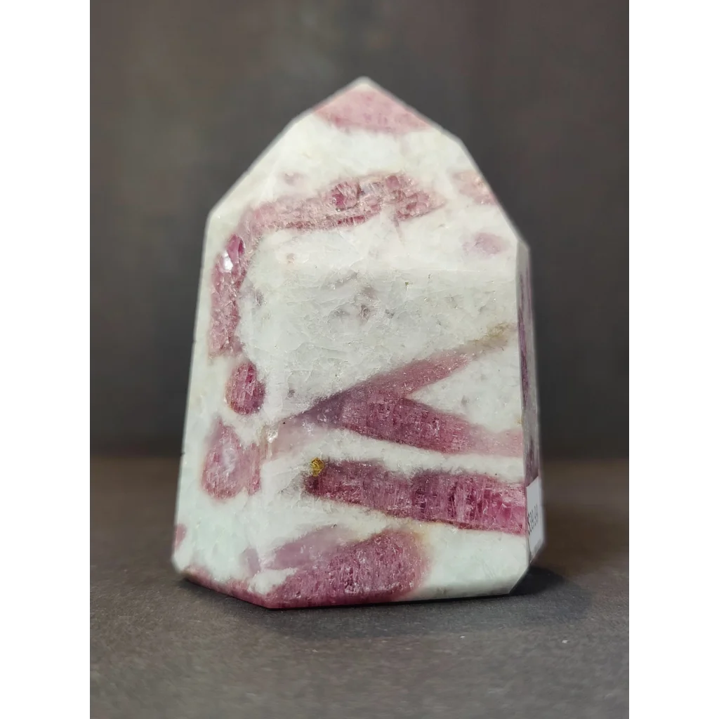 A polished pink and white rhodochrosite crystal geode quartz polished obelisk tower sculpture with a faceted pyramid top
