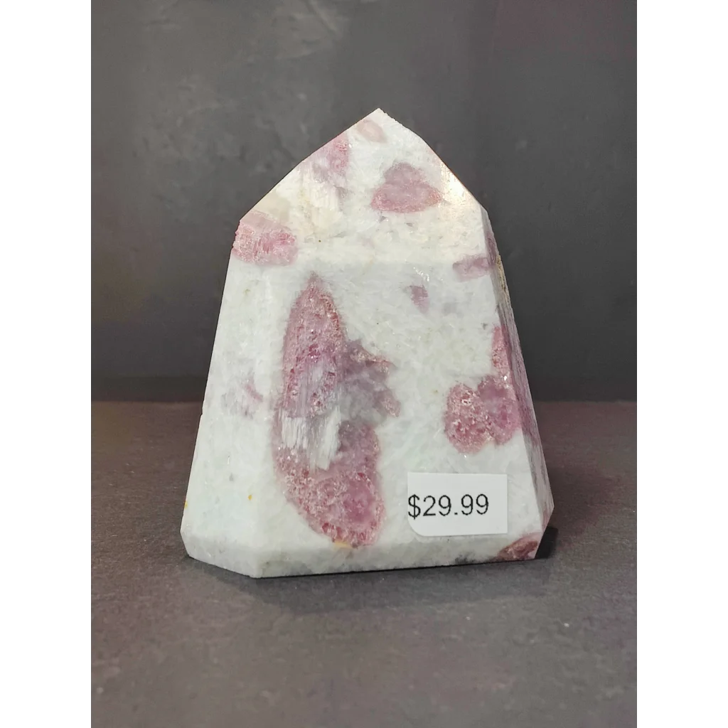 A polished pink and white rubellite quartz polished obelisk tower sculpture with a faceted geometric design