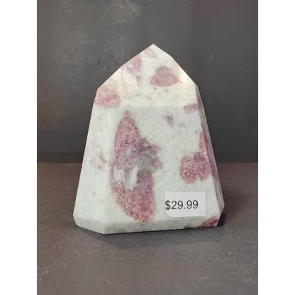 A polished pink and white rubellite quartz polished obelisk tower sculpture with a faceted geometric design