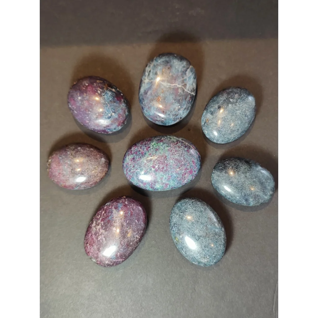 Seven polished oval-shaped ruby kyanite spheres with purple pink and gray hues for healing and display use