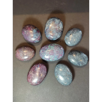 Seven polished oval-shaped ruby kyanite spheres with purple pink and gray hues for healing and display use