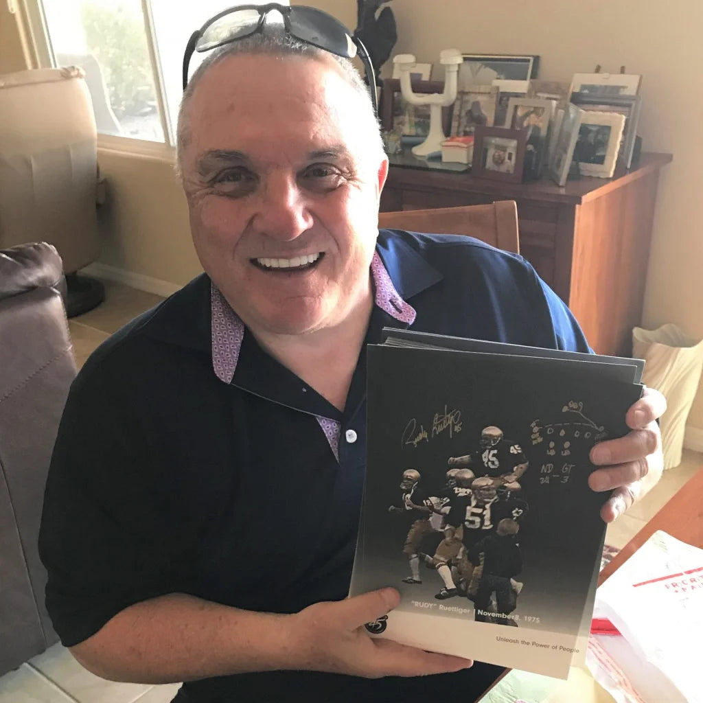 Autographed Rudy Ruettiger Notre Dame 8x10 photo on black leather football book cover