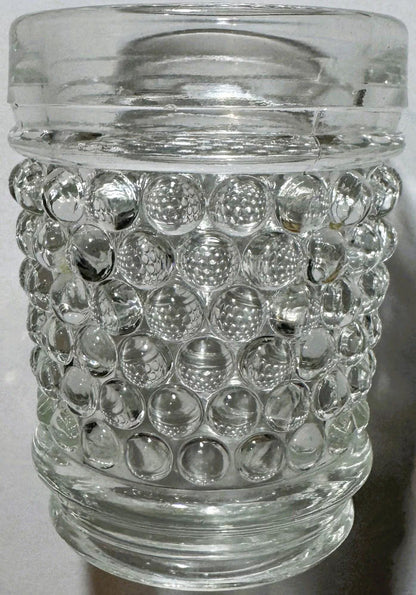 Clear hobnail shot glass standing upright, with a ridged band at the rim and a ribbed ring at the base.