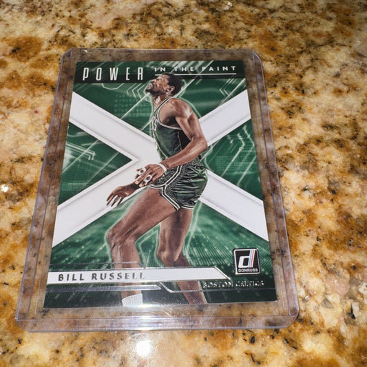 A 2021-22 Panini Donruss Power in the Paint basketball card featuring Bill Russell in a clear protective case, displayed flat on a speckled granite countertop.