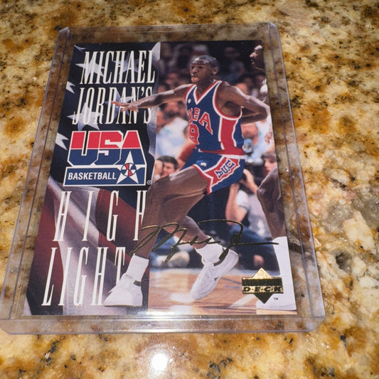 Signed 1994 Upper Deck Michael Jordan High Light insert card displayed on speckled granite countertop, showing player in USA Basketball red jersey.
