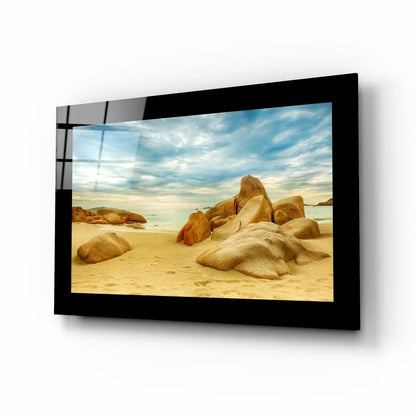 Black-framed glass wall art of beach scene with golden rocks and turquoise waters