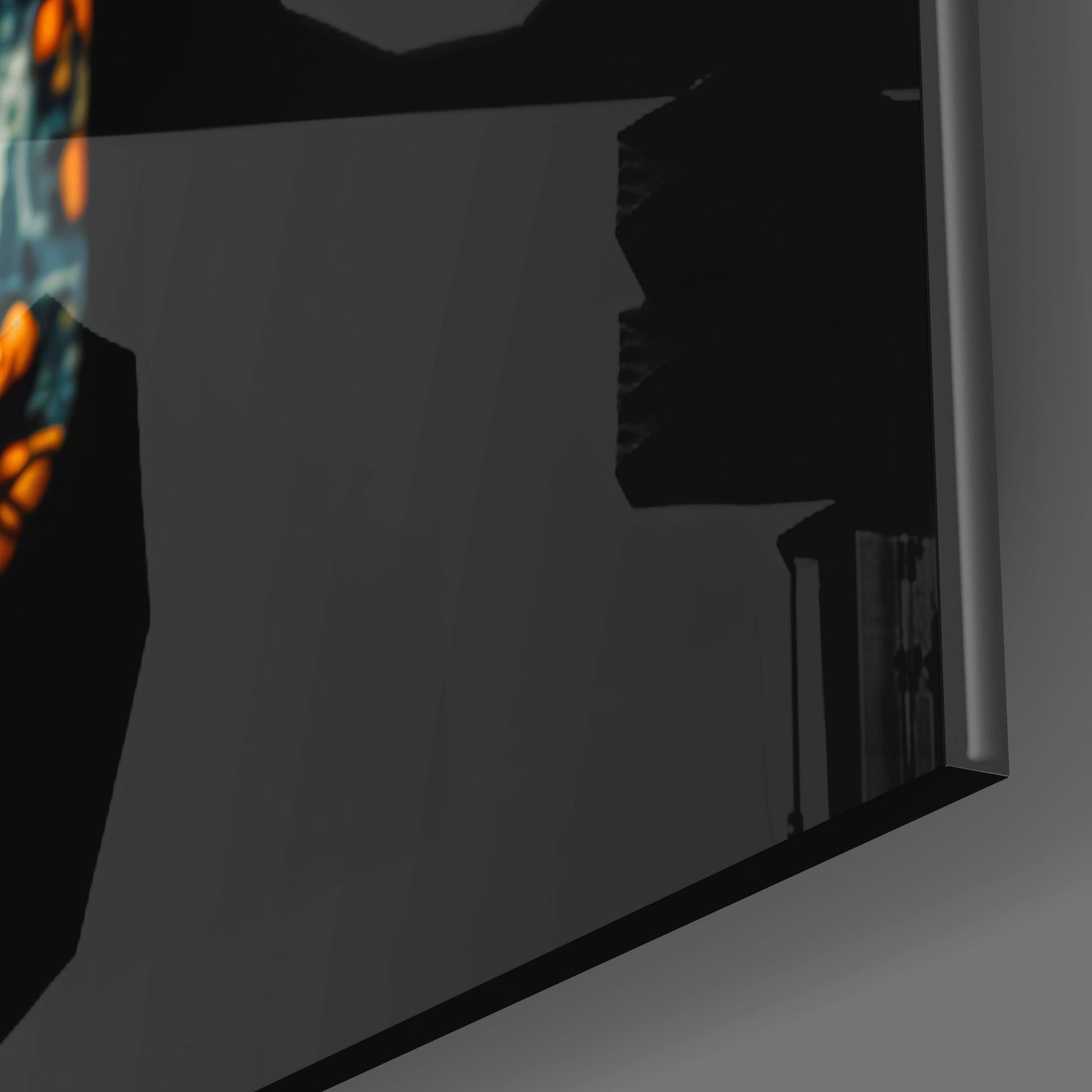 Side profile view of black framed glass wall art with orange and teal floral skull design visible on left edge.