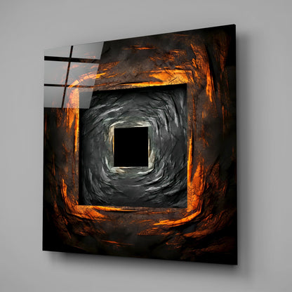 Square glass wall art with concentric square frames featuring orange and black brushstroke textures, mounted on gray wall.