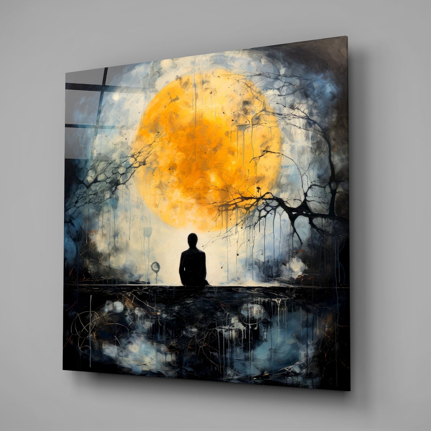 A silhouetted figure sits gazing at a large golden moon above dark water, surrounded by bare branches and blue-grey tones on glass wall art.