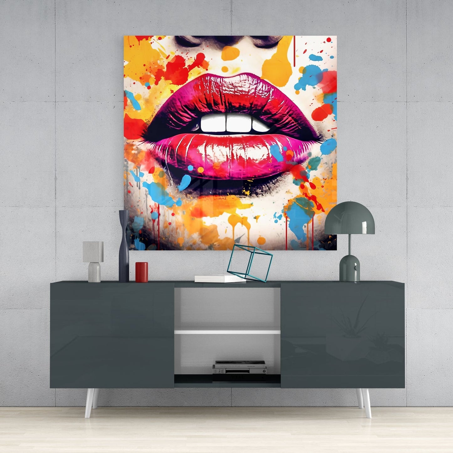Colorful glass wall art displaying vibrant pink lips with paint splashes mounted above a gray media console in a modern interior setting.
