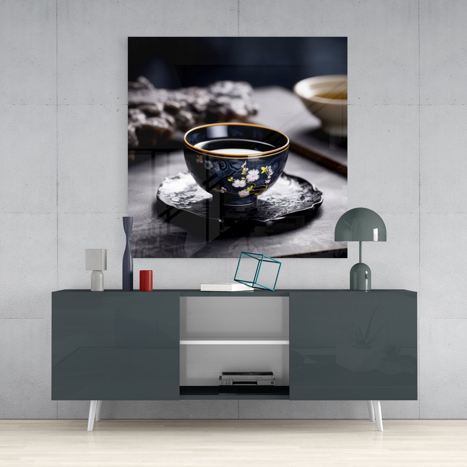 Dark porcelain tea bowl with gold rim and floral design displayed on textured black coaster in styled room setting.