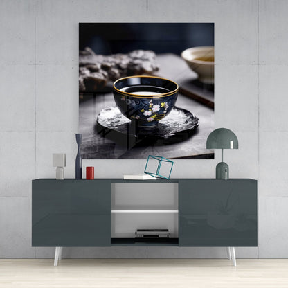 Dark porcelain tea bowl with gold rim and floral design displayed on textured black coaster in styled room setting.