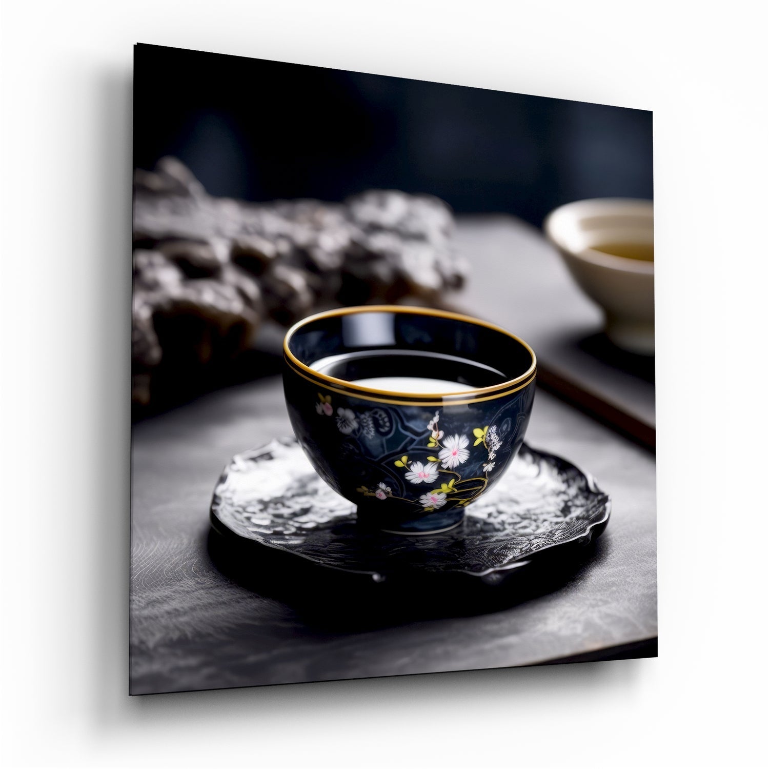 Black porcelain tea cup with gold rim and floral design sitting on dark coaster, filled with pale tea, blurred background.
