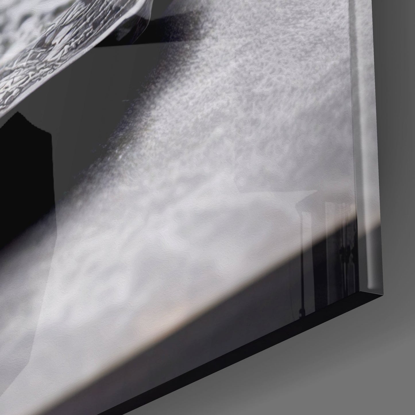 Close-up detail of textured glass surface with water droplets and shadow casting across frosted white panel.