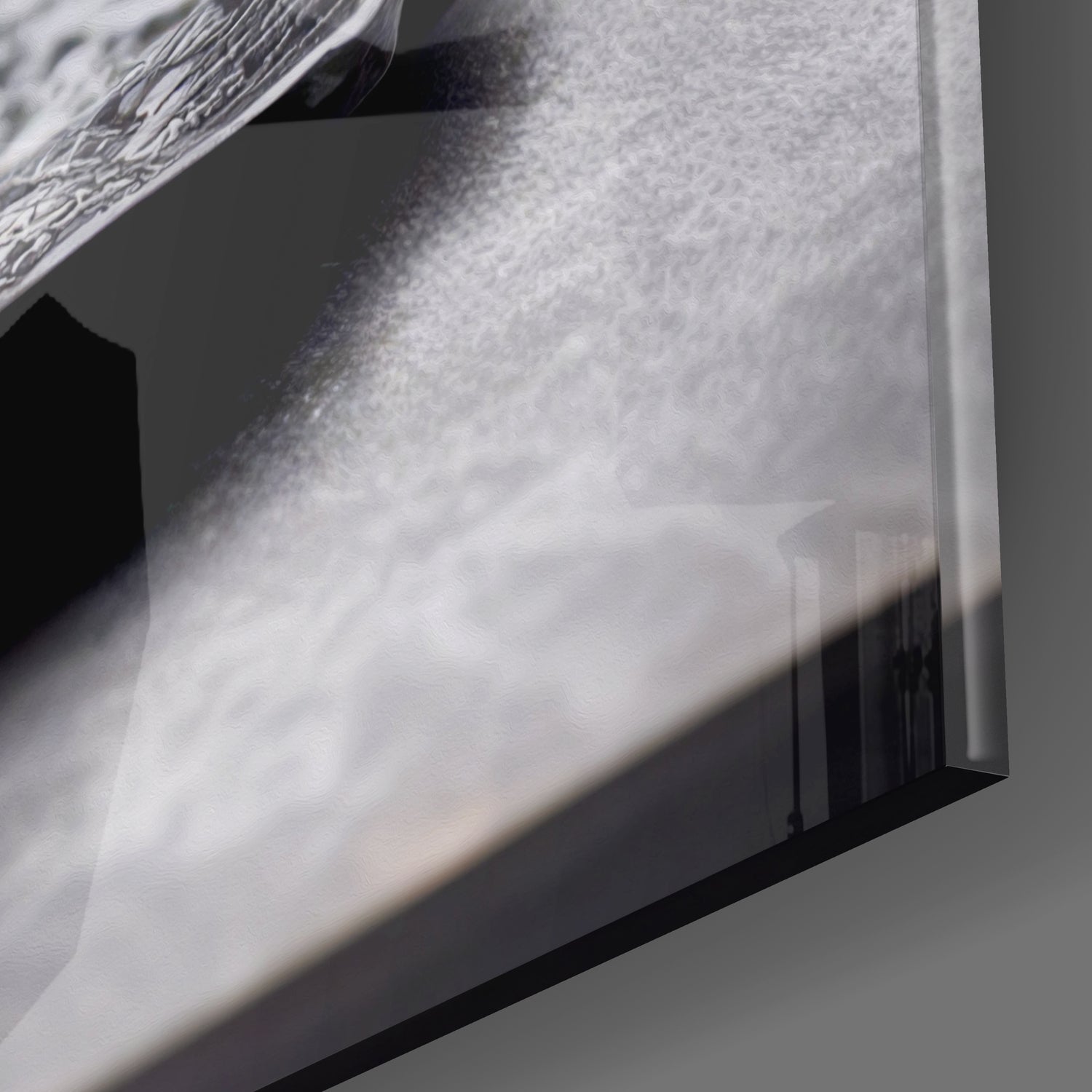 Close-up detail of textured glass surface with water droplets and shadow casting across frosted white panel.