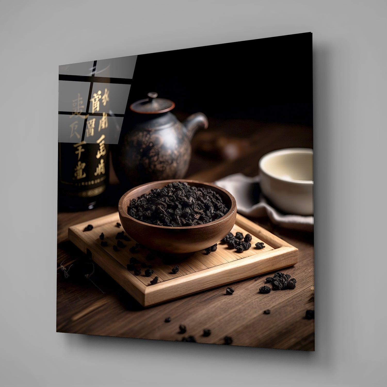Dark oolong tea leaves in wooden bowl on tray with black teapot and white cup on wooden surface.