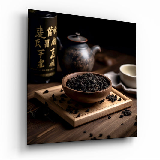 Wooden tray with wooden bowl of dark tea leaves, black teapot, white cup, and dark bottle with gold Chinese characters on wooden surface.