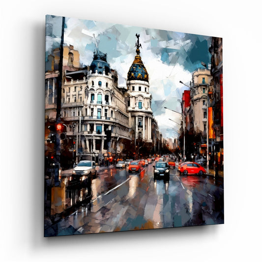 Angled perspective of glass wall art depicting a wet Madrid street with ornate architecture, red taxis, and a blue-domed building under cloudy skies.