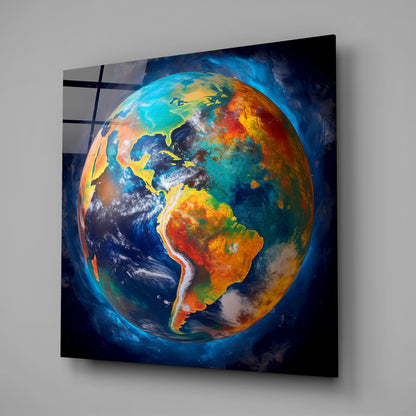 Colorful glass wall art displaying Earth with vibrant blues, oranges, yellows, and greens, mounted at an angle against a gray wall.