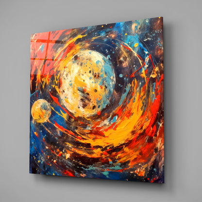 Angled view of glass wall art featuring a luminous celestial sphere surrounded by swirling orange, red, yellow, and blue brushstrokes with splattered accents.
