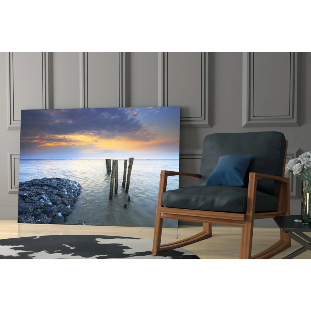 Serene sunset glass wall art with wooden pilings and rocks in modern room