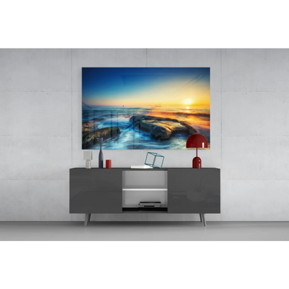 Vibrant sunset ocean glass wall art with rocky shore and golden horizon