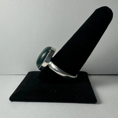 Sleek silver serpentine ring with oval dark green stone in polished band