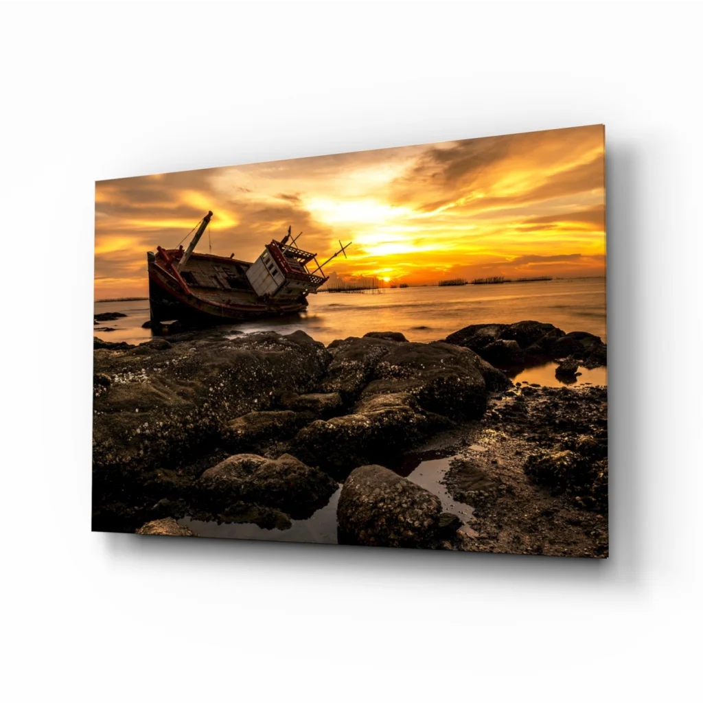 Weathered red fishing boat on rocky shore at sunset, glass wall art